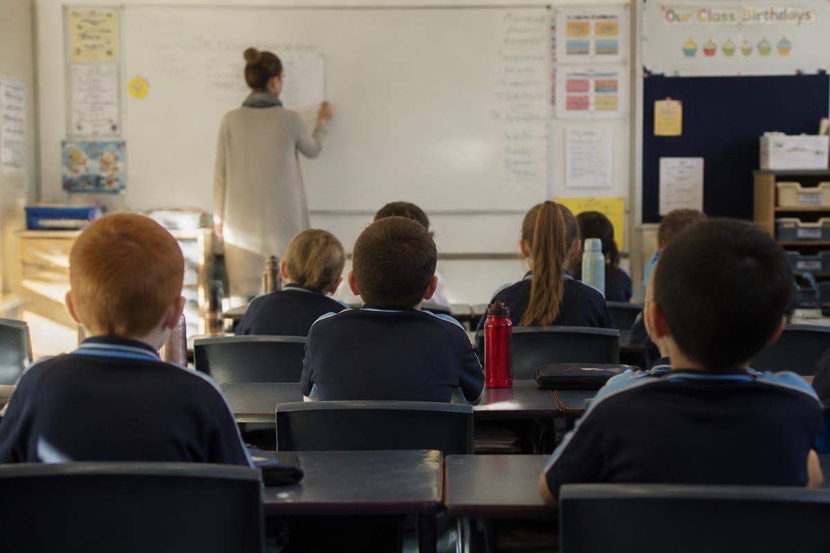 Primary school classroom with a teacher at the whiteboard and students at desks